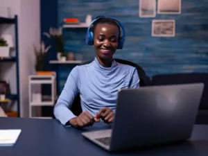 black-woman-good-mood-wearing-headset-listening-music-working-deadline-from-home-office-sitting-desk-african-freelancer-creating-new-project-working-late